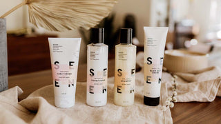 SEEN haircare products lined up on a brown cloth with a dried fan palm leaf in the background