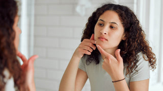 Woman popping a pimple in the mirror