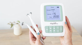 hands holding a MyoLift TriWave device with probes and plant in background