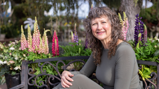 Jeana LeClerc on a bench with flowers in the background.