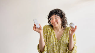 Woman holding two skincare products with a questioning gesture