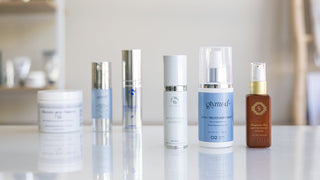 Collection of three skincare products on a table with three products blurred out in background.