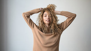 Woman with her arms above her head with her hands in her hair.