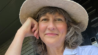 Jeana wearing a sunhat smiling with glowing skin