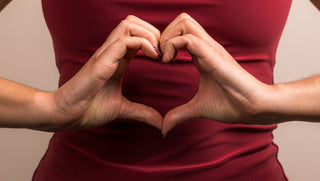 Woman holding hands in the shape of a heart in front of her stomach