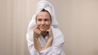 Woman fresh out of the shower with white bathrobe and hair wrapped in a towel.
