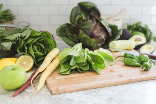 Lettuces, carrots, apple, citrus, avocado on a cutting board