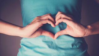 Woman holding hands in the shape of a heart in front of her stomach