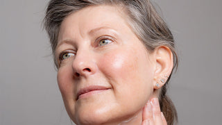 Jeana LeClerc gazing away from the camera with a hand on  her neck.