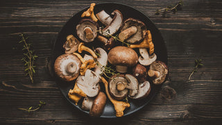 A variety of mushrooms in a bowl on a wooden table