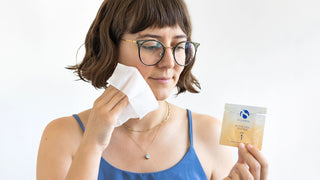 A person applies an iS Clinical peel pad to their face.