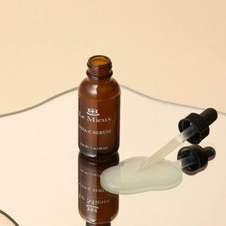 Le Mieux Vita-C Serum bottle with dropper and golden vitamin C serum on a reflective mirror surface.