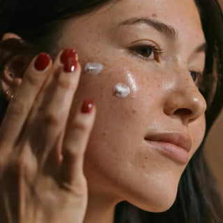 Woman applying Sorella Lemon Lightening Serum to her cheek to help fade dark spots, improve skin tone, and restore radiance
