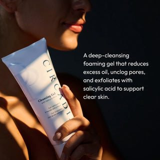 Woman holding Circadia Cleansing Gel with Salicylic Acid tube, a deep-cleansing foaming gel that reduces excess oil, unclogs pores, and exfoliates with salicylic acid to support clear skin