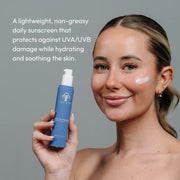 Woman holding Circadia Light Day Sunscreen SPF 37 with sunscreen applied to cheek — lightweight non-greasy daily sunscreen that protects against UVA/UVB damage while hydrating and soothing the skin
