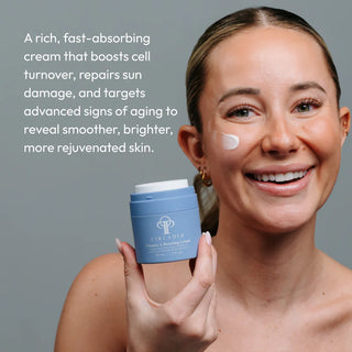 Woman holding Circadia Vitamin A Boosting Cream jar with cream applied to cheek — rich retinol cream that boosts cell turnover, repairs sun damage, and targets advanced signs of aging for smoother, brighter skin