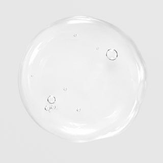 Close-up of Hale & Hush Remedy Rehab Oil showing a lightweight, clear oil texture with small bubbles on a light gray background