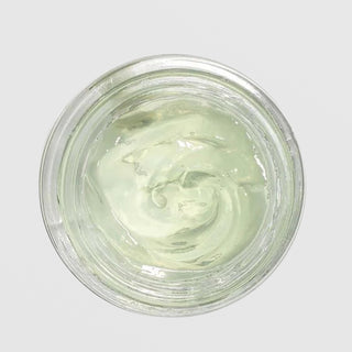 Overhead close-up of an open jar of Farmhouse Fresh Watercress Hydration Cascade Retinol Geléé Moisturizer showing its light green gel-cream texture with a swirled appearance, against a light gray background.
