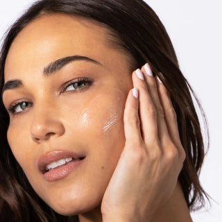 Woman applying ALASTIN HA IMMERSE Serum to cheek with fingertips