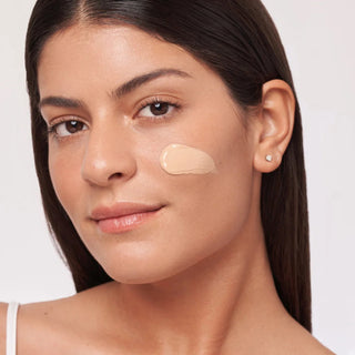 Woman applying ALASTIN HydraTint Pro Mineral Sunscreen tinted cream to cheek