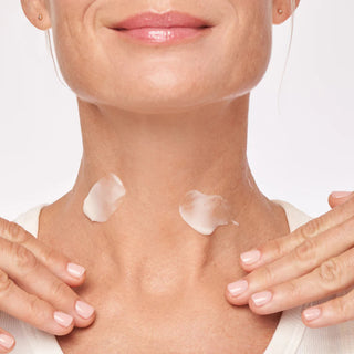 Woman applying ALASTIN Restorative Neck Complex cream to neck and décolletage