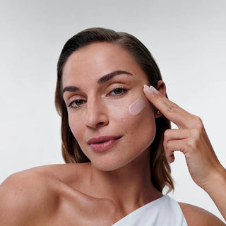 Woman applying ALASTIN Restorative Skin Complex serum to under-eye area