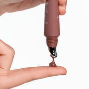 Anfisa Skin AN-GLOSS Ceramide Lip Tint in Spice Cake being squeezed onto finger showing warm brown tinted formula texture