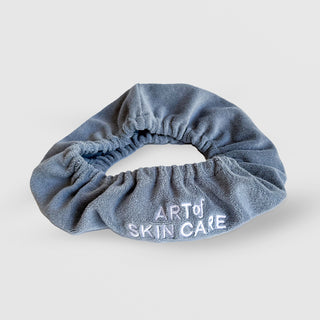 Blue scrunchie with 'Art of Skin Care' text on a white background