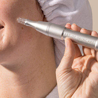 Model holding Art of Skincare nano infusion pen to cheek, silver device with nano cartridge attached
