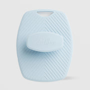 Art of Skin Care large blue silicone body scrubby with chevron texture and a finger loop handle, featuring an embossed Art of Skin Care grip pad, displayed against a light gray background.