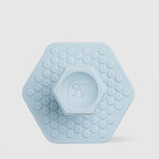 Art of Skin Care small blue silicone face scrubby in a hexagonal shape with honeycomb texture and a raised AS logo grip on the back, displayed against a light gray background.