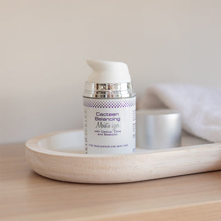 A botle of Skin Script Cacteen Balancing Moisturizer sits on a wooden tray with its cap off.