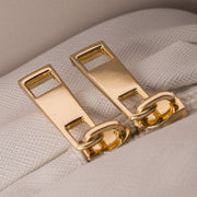 Close-up of Art of Skincare Signature Cosmetic Case gold zip pulls against white textured fabric