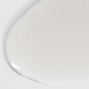 Close-up of Hale & Hush Soothe Essence showing a lightweight, milky white essence texture on a light gray background