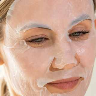 Close-up of woman's face wearing a hydrating sheet mask, showing full facial coverage and fit