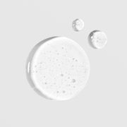 Close-up of Colorescience Total Eye Concentrate Serum texture showing a clear lightweight gel formula with fine bubbles on a light gray background