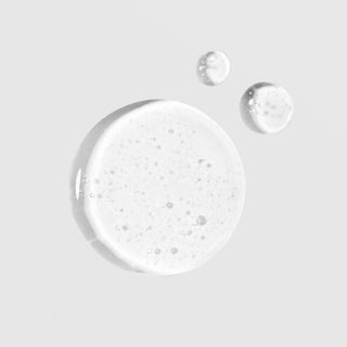 Close-up of Colorescience Total Eye Concentrate Serum texture showing a clear lightweight gel formula with fine bubbles on a light gray background