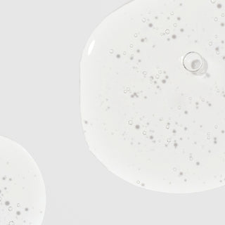 Close-up of Corthe Dermo Bright C Ampoule showing a lightweight, water-thin clear serum with tiny bubbles on a light gray background