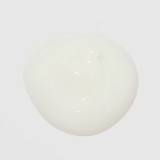 Close-up of Corthe Dermo Pure First Aid Lotion showing a lightweight, milky white lotion drop texture on a light gray background