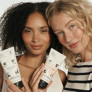 Two women with curly hair — one with tight dark curls, one with loose blonde waves — each holding a tube of SEEN Curly Creme in fragrance free and scented versions (6 fl oz / 177 ml), with the instruction to apply a quarter-size amount to damp hair from roots to ends and air-dry or heat-style.