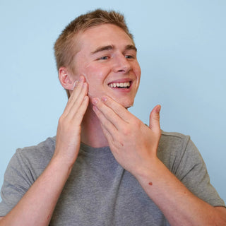Smiling man massaging Face Reality Antioxidant Scrub onto acne-prone skin – gentle exfoliating scrub for men and women