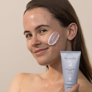 Woman applying Face Reality Cran-Peptide Cream to cheek – rich restorative peptide moisturizer, acne-safe for dry skin