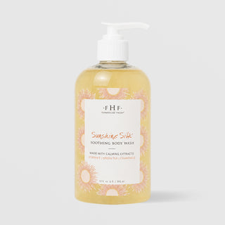 Farmhouse Fresh Sunshine Silk Soothing Body Wash (12 fl oz / 355 ml) in a clear pump bottle with a golden yellow formula and a sunburst-patterned label, formulated with vitamin E, green tea, and chamomile, displayed against a light gray background.