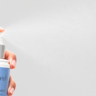 Hand spraying GlyMed Plus CBD Skin Mist showing fine mist dispersing from the bottle