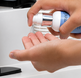 Dispensing GlyMed Plus Pigment Brightening Serum from white pump bottle into palm of hand