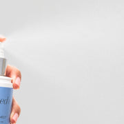 Hand spraying GlyMed Plus Skin Recovery Mist showing fine mist dispersing from the bottle