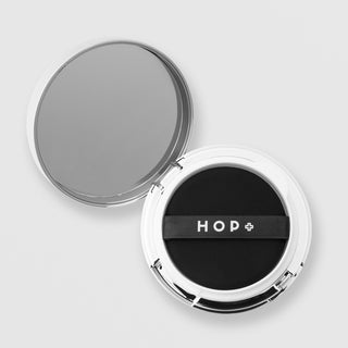 HOP+ Volume Shield Cushion open compact showing black cushion puff with HOP+ branded strap and built-in mirror, silver chrome case