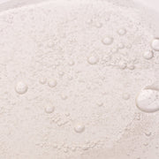 Close-up of Hale & Hush Clarify Wash gentle gel cleanser texture showing clear formula with fine bubbles and water droplets on light background