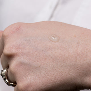 Close-up of a drop of Hale & Hush Rare C Serum showing lightweight clear gel texture swatched on back of hand