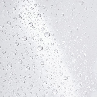 Hydrinity Hyacyn Active Purifying Mist texture close-up showing ultra-fine clear water droplets on light gray surface.